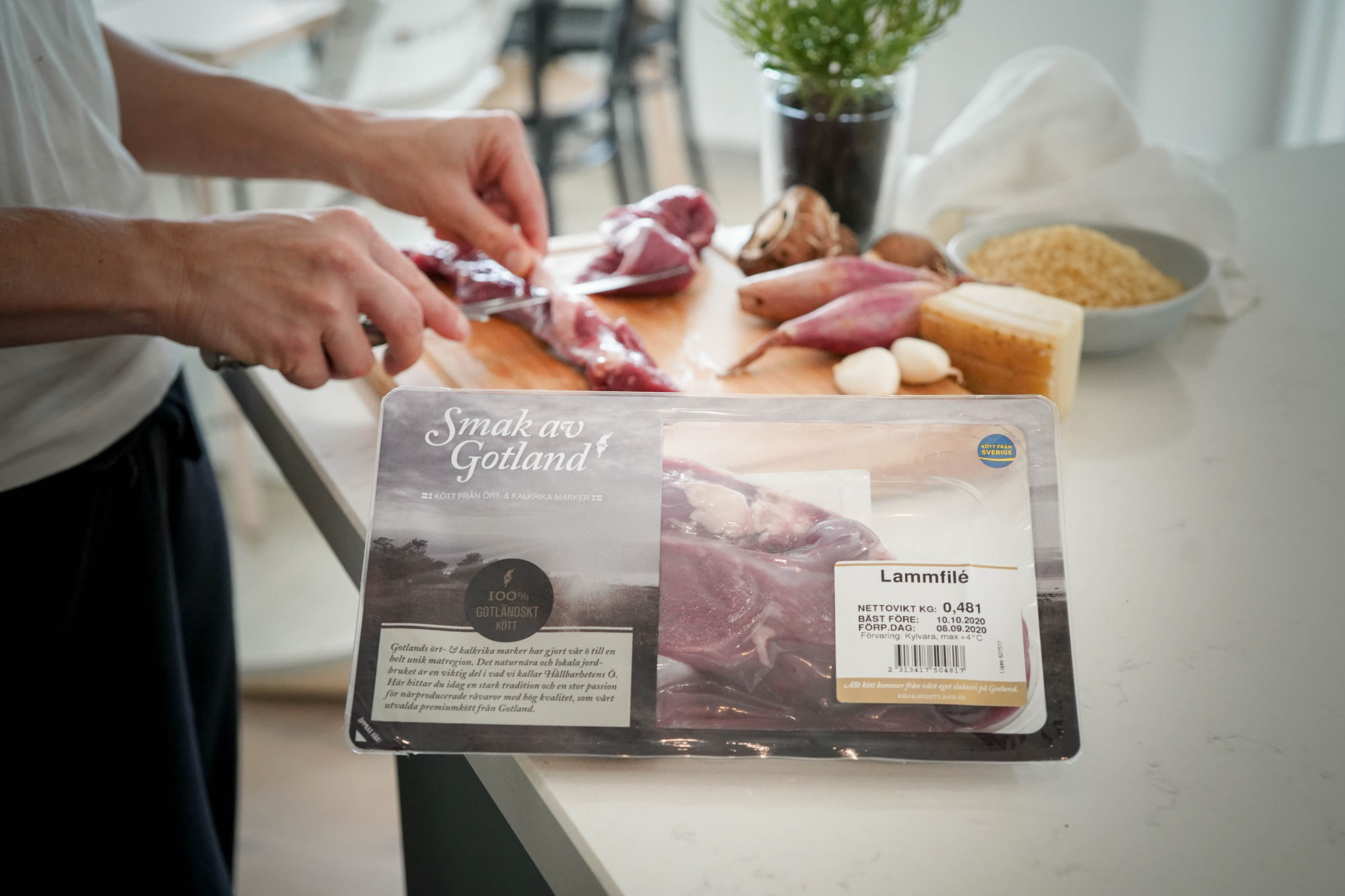 Person som skär lammfilén i bakgrunden av förpackningen samt förbereder tillbehör